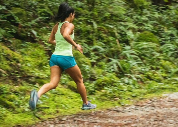 Photo by Greg Rosenke woman in white tank top running on dirt road during daytime
