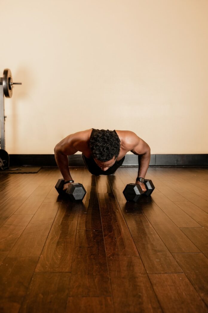 Photo by Meagan Stone man in black tank top and black shorts holding black dumbbells
