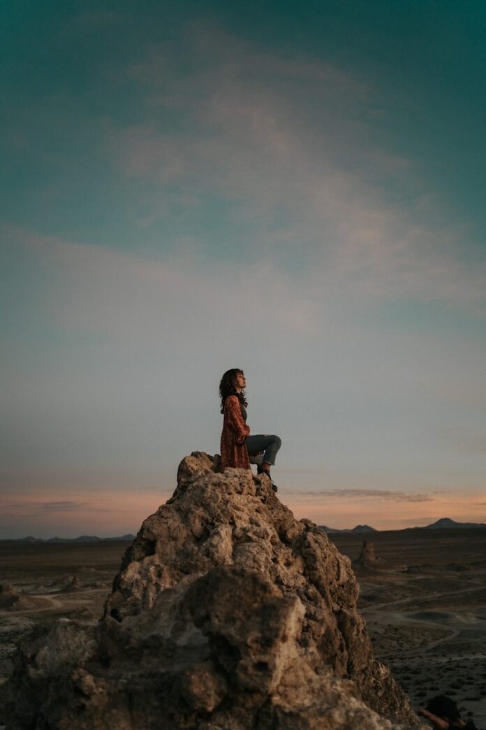 Photo by Johnny Vargas A person sitting on top of a large rock