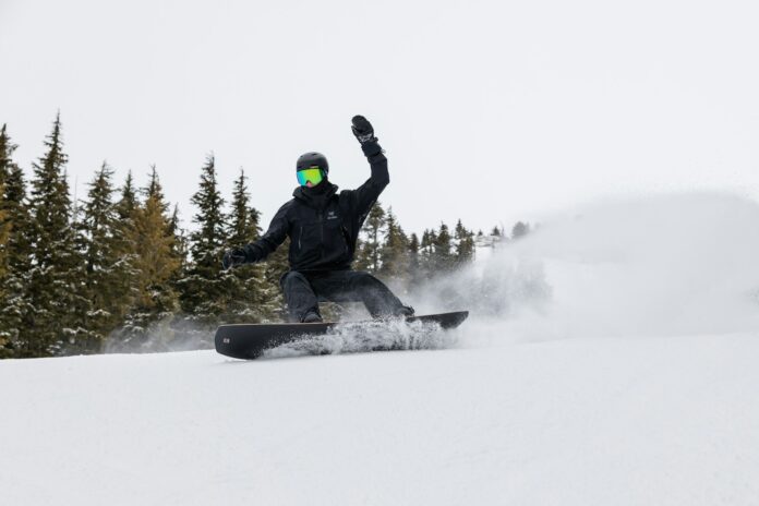 Photo by Greg Rosenke a man riding a snowboard down a snow covered slope