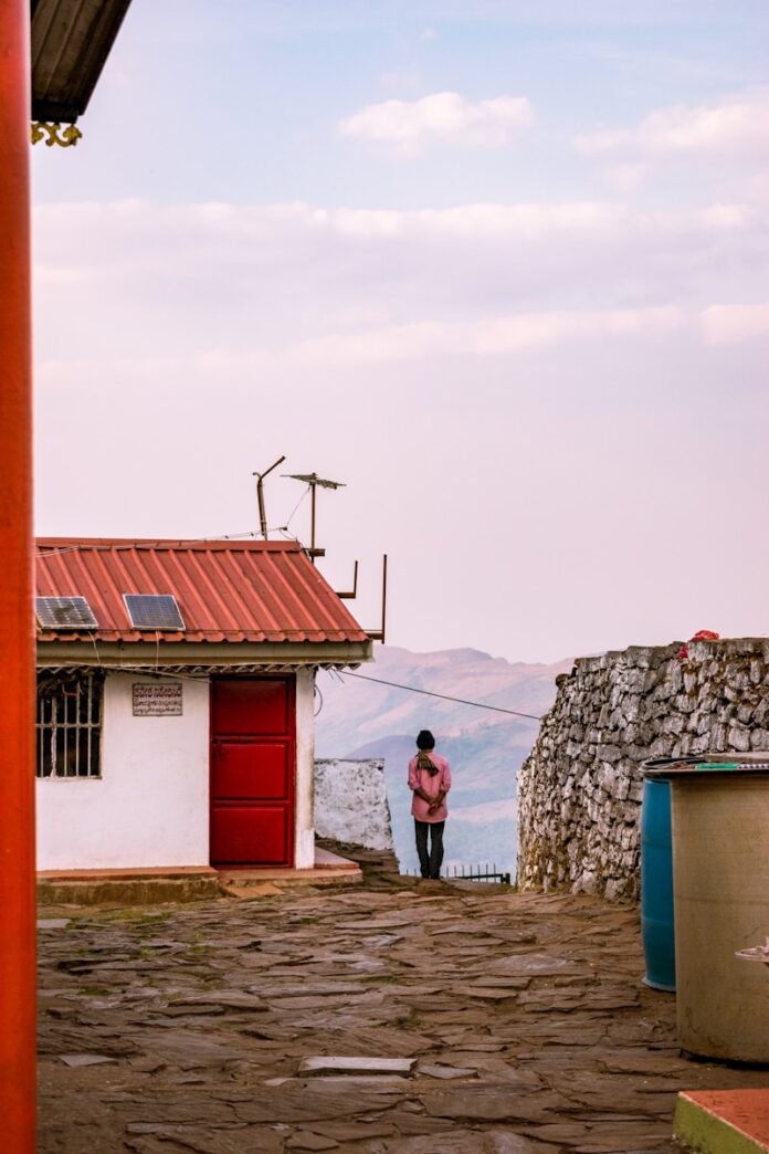 Photo by Shubhomoy Ball A man standing in front of a building with a red door