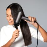 ‘건강한 두피와 윤기나는 모발’…일상 속 실천하는 헤어 루틴이 인기 a woman blow drying her hair with a hair dryer