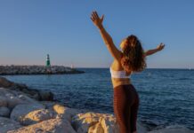 “마음도 체력처럼 단련…일상 속 정신건강 챙기는 5가지 루틴” woman in white sports bra and black bottoms standing on seashore