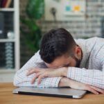 만성피로, 현대인의 고민… 일상 속 새 에너지 찾는 법 a man sitting at a desk with his head in his hands